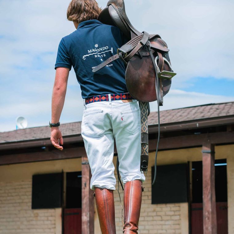 A rider carrying his saddle
