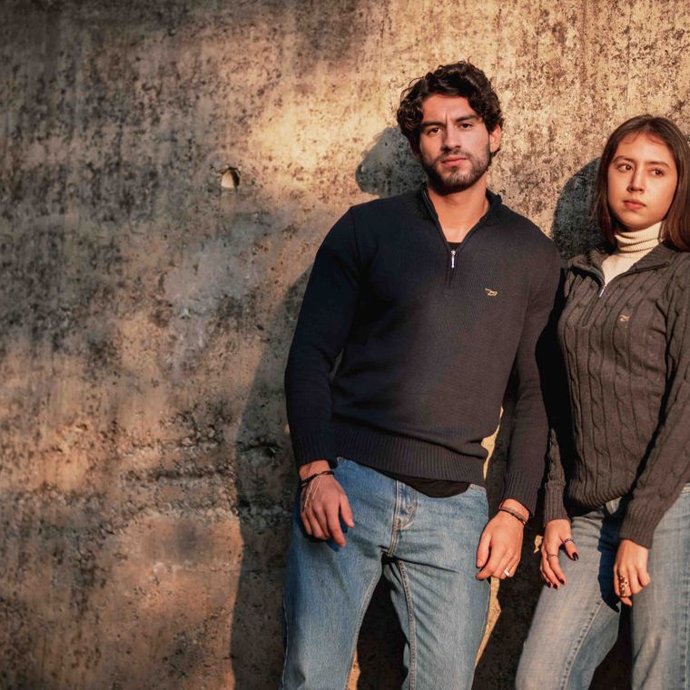 Two people posing against a stone wall
